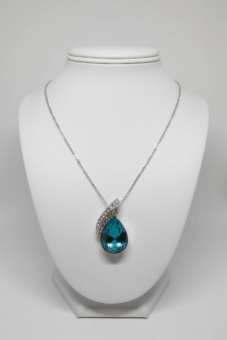Necklace with a green emerald teardrop pendant on a white mannequin bust.