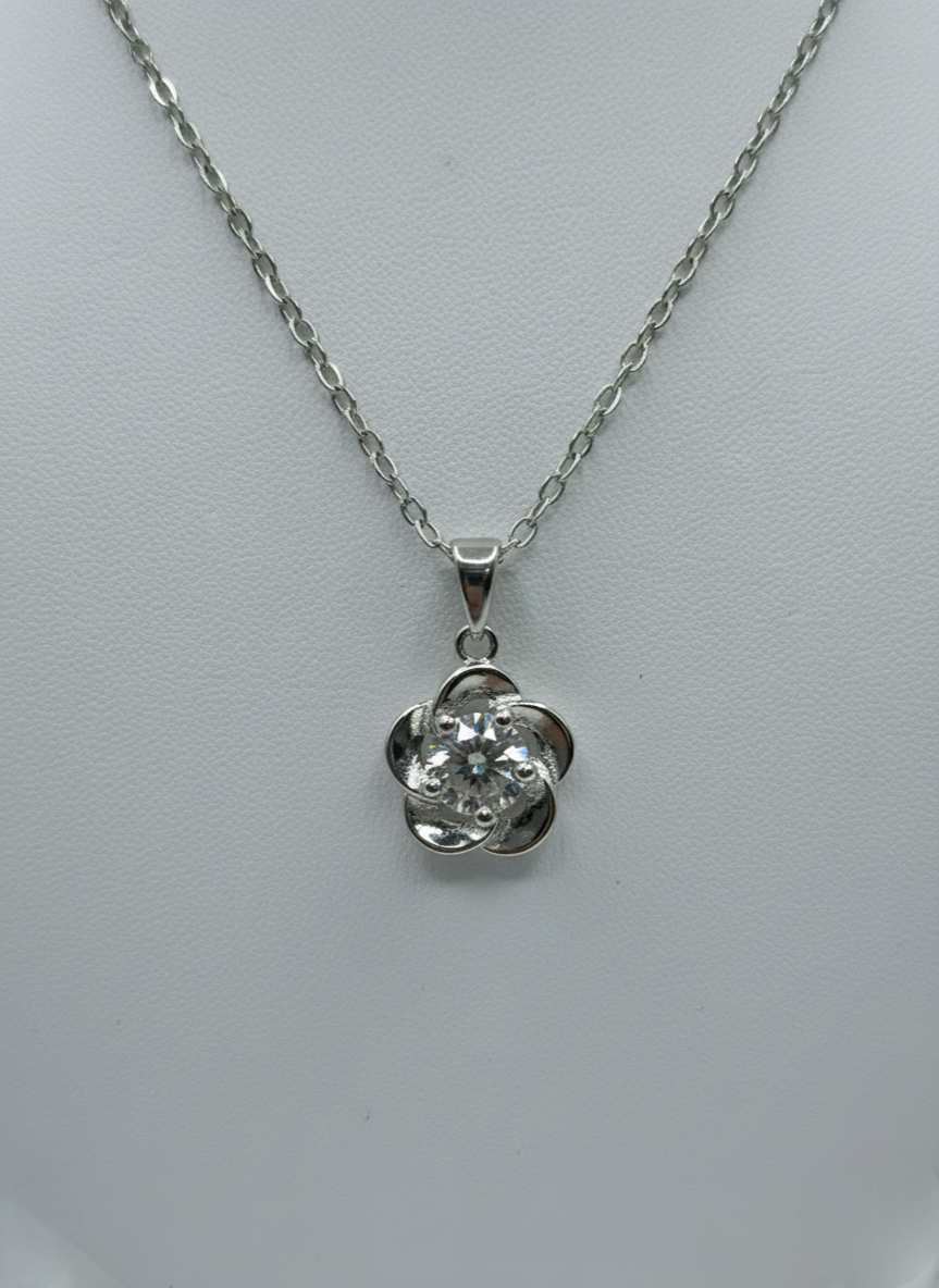 Silver necklace with a flower-shaped pendant on a light gray background